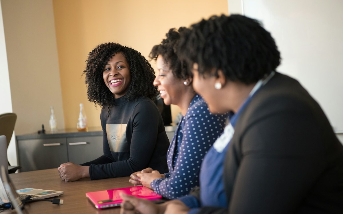 Tres compañeras conversando en una mesa de trabajo