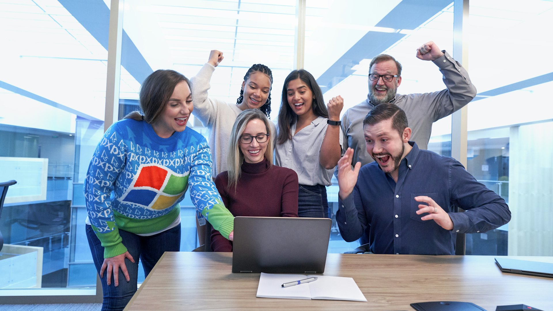 Equipo celebrando alrededor de un portátil en una oficina